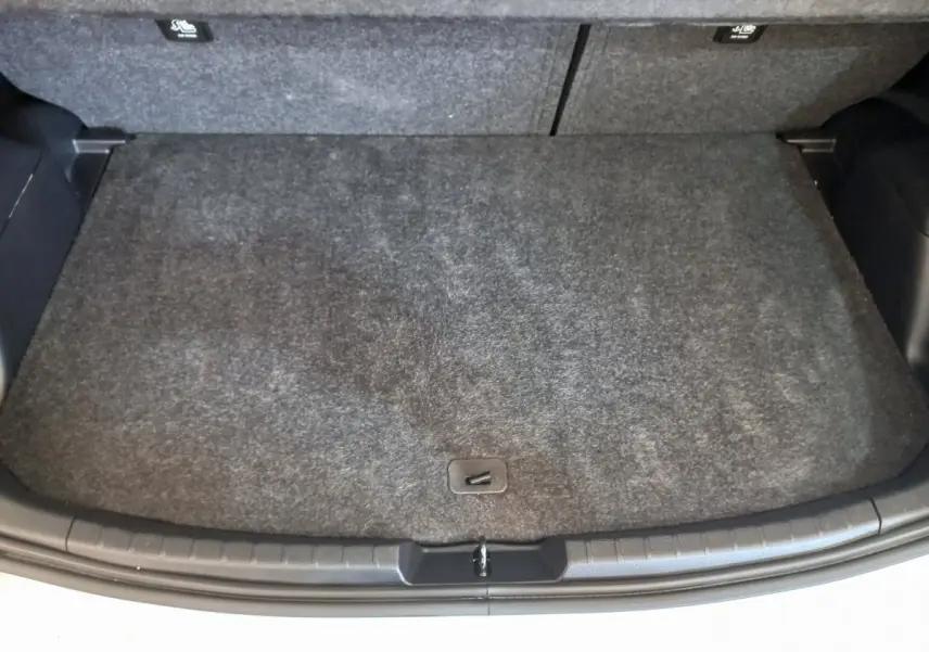 Coffre vu de dessus d'une Toyota Yaris blanche 2019, avec tapis de sol gris foncé et banquette arrière rabattable.
