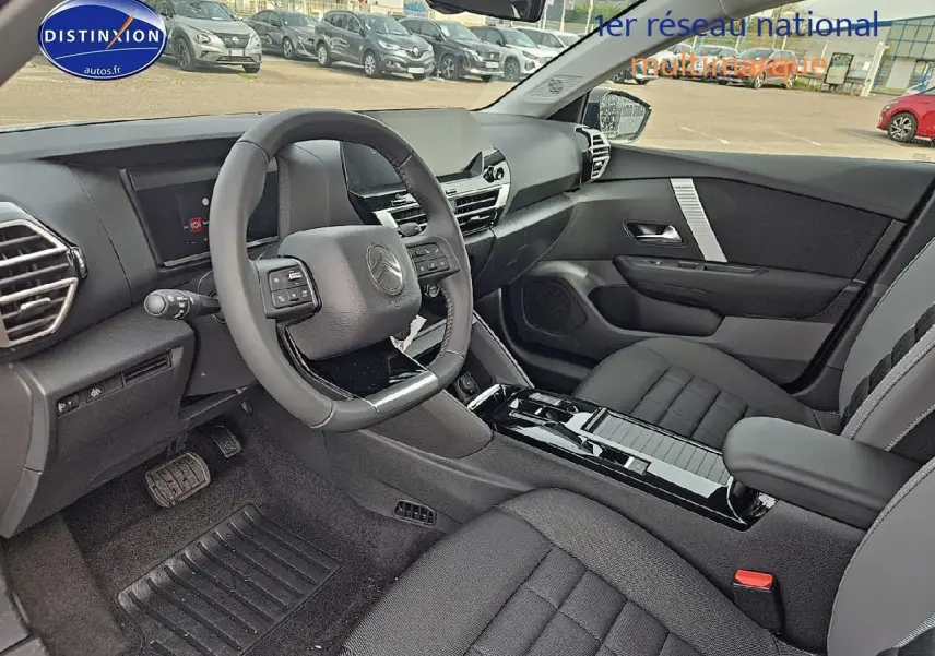 Intérieur avant droit de la Citroën C4 1.2 hybride 145 plus avec sièges tissu noir et console centrale brillante noire.