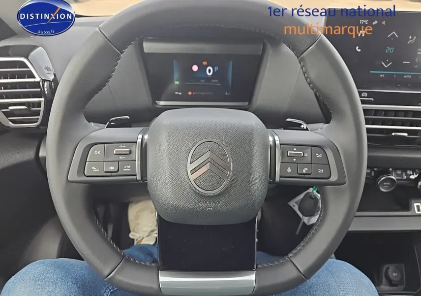Vue centrée sur le volant cuir noir du Citroën C4 1.2 hybride 145 plus avec tableau de bord numérique en arrière-plan.