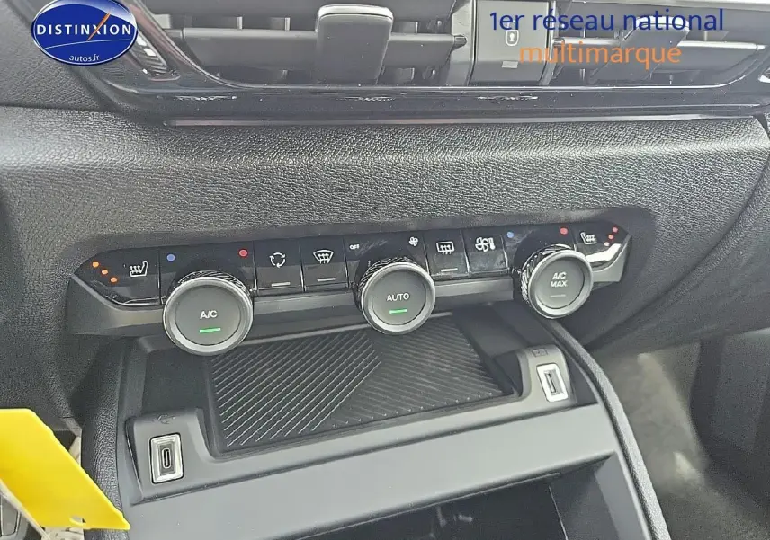 Vue rapprochée de la console centrale avec commandes climatisation et deux prises USB visibles, intérieur noir texturé.