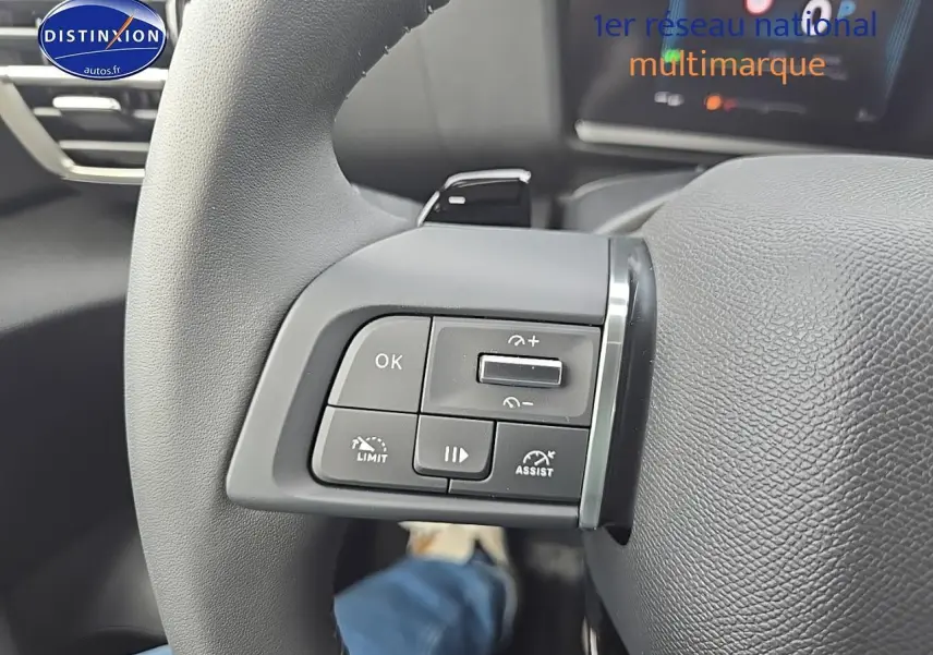 Gros plan sur les commandes au volant côté gauche du Citroën C4 blanc okenite, avec palettes de changement de vitesse.