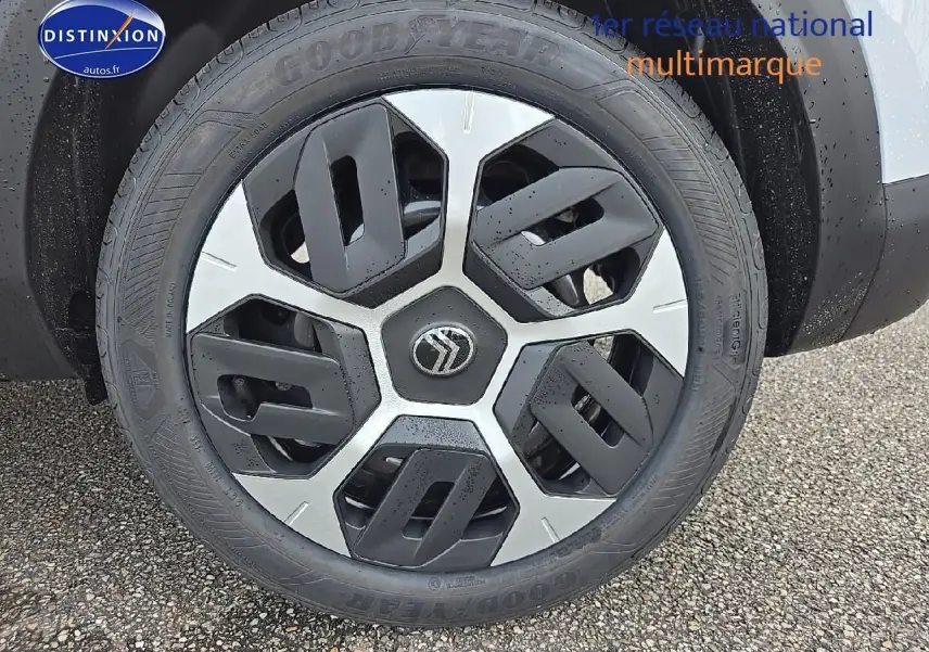 Gros plan sur la roue avant droite avec jante 18 pouces Aerotech noire et argentée d'une Citroën C4 blanc Okenite.