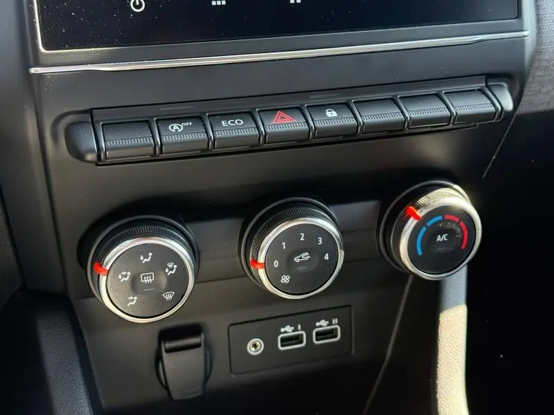 Gros plan sur les commandes de climatisation et boutons fonctionnels du tableau de bord de la Renault Clio gris schiste 2025.