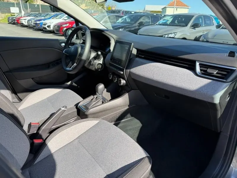 Vue intérieure côté conducteur de la Renault Clio 2025 avec sièges tissu gris et tableau de bord moderne.
