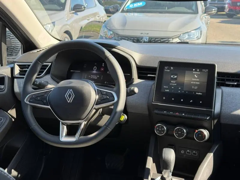 Vue intérieure frontale du tableau de bord gris clair et volant cuir noir de la Renault Clio 2025 TCe 90ch Evolution.