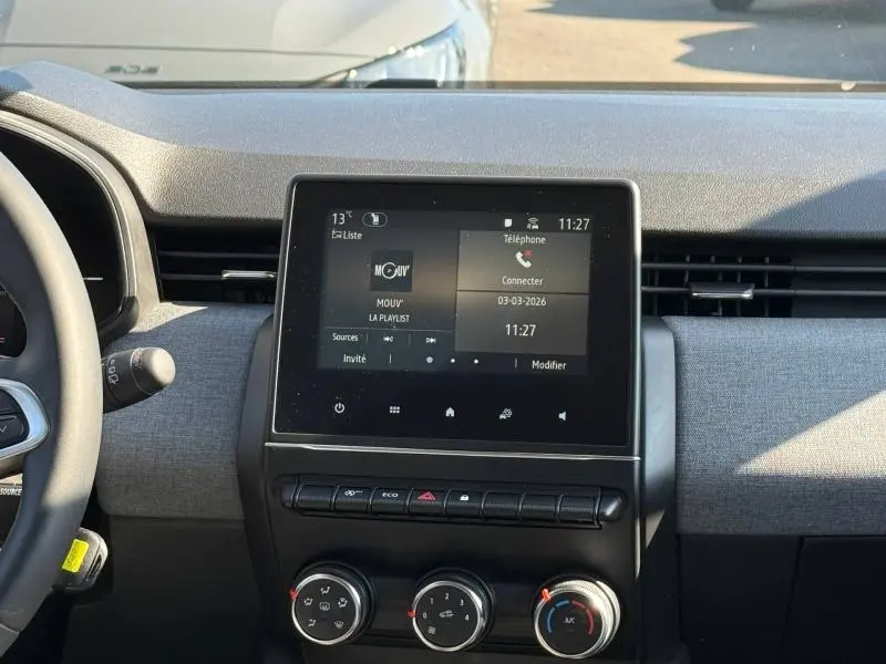 Vue intérieure du tableau de bord de la Renault Clio gris schiste, avec écran tactile central et commandes de climatisation.