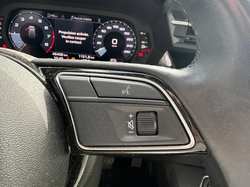 Gros plan sur les commandes vocales et volume au volant cuir noir de l'Audi A3 Sportback 35 TFSI 2022, tableau de bord numérique visible.