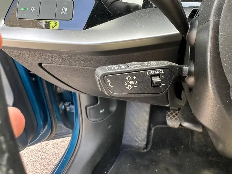 Détail du commodo de régulateur de vitesse sur le côté gauche du volant d'une Audi A3 Sportback bleu Atoll métallisé.