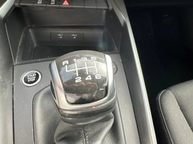 Gros plan sur le levier de vitesse manuel noir de l'Audi A3 Sportback 35 TFSI, avec bouton Start Engine Stop visible à gauche.