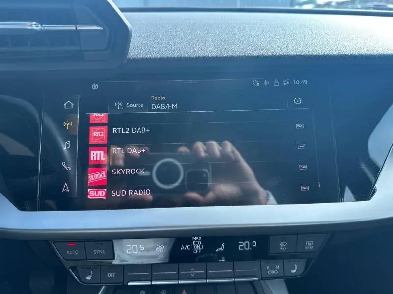 Écran tactile central de l’Audi A3 Sportback 35 TFSI 2022 affichant les stations radio DAB/FM, avec commandes climatisation en dessous.