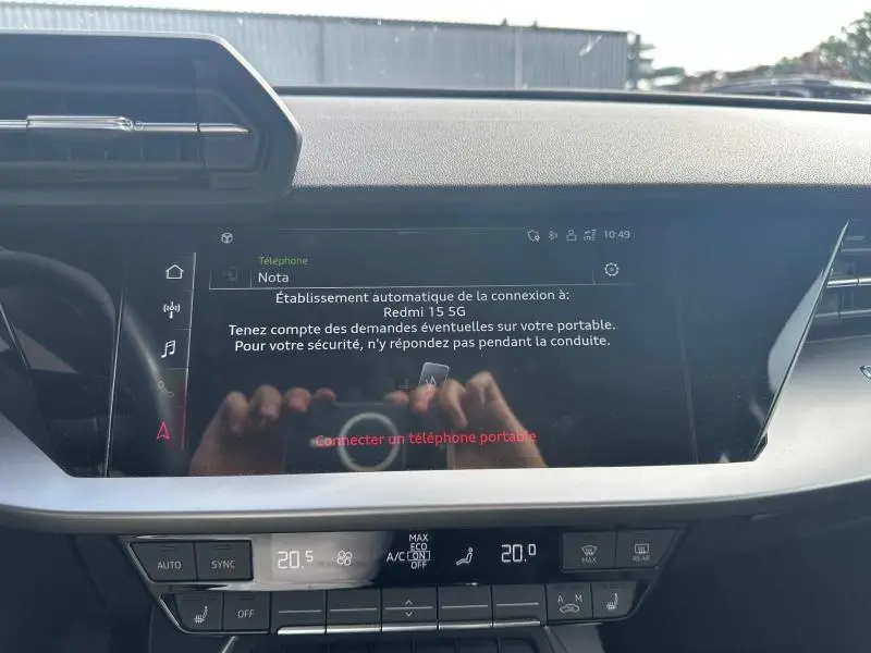 Vue rapprochée du tableau de bord de l'Audi A3 Sportback 35 TFSI 150ch Design 2022, écran tactile et commandes climatisation visibles.