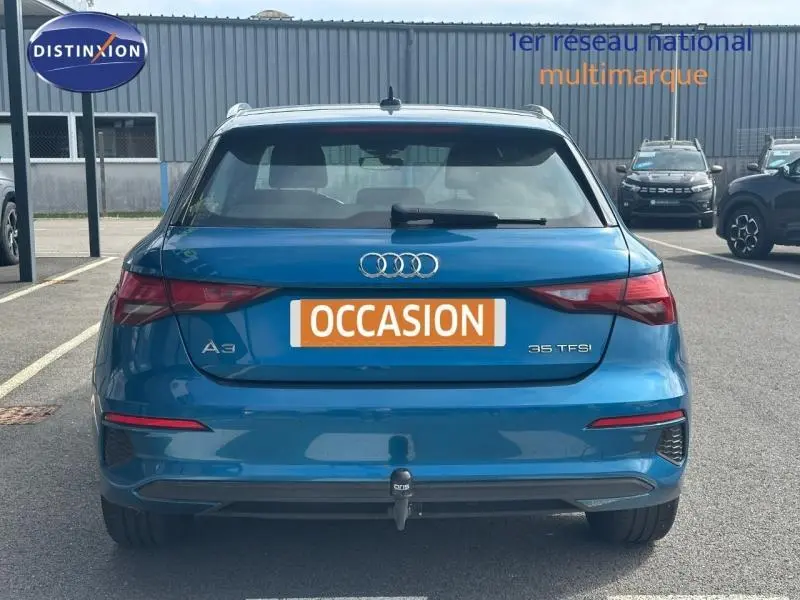 Vue arrière d'une Audi A3 Sportback 35 TFSI bleu Atoll métallisé avec attelage visible sur parking.