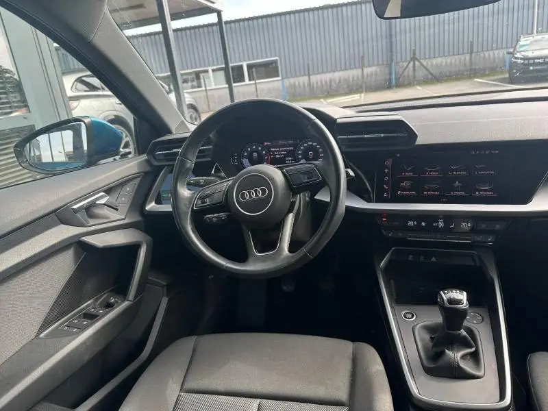 Vue intérieure avant centrée sur le volant cuir multifonction et la console avec boîte manuelle de l'Audi A3 Sportback bleu Atoll.