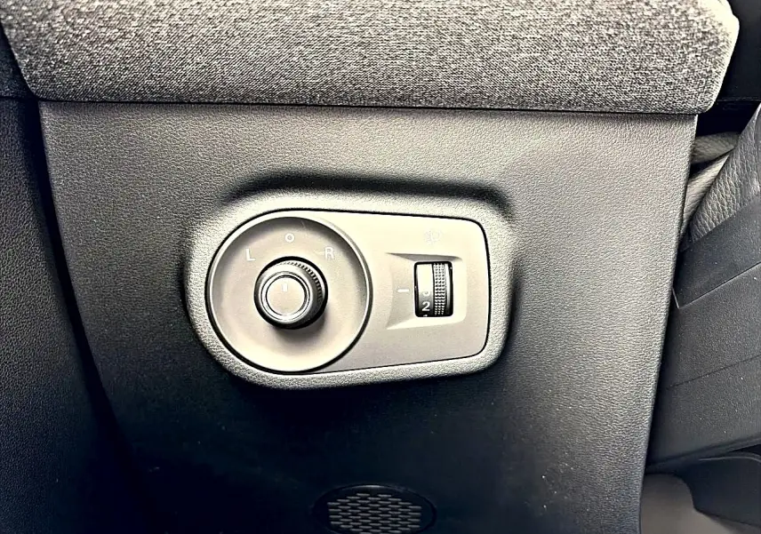 Gros plan sur les commandes de réglage des rétroviseurs et des phares d’un MG Motor ZS 1.5 hybrid gris Camden.