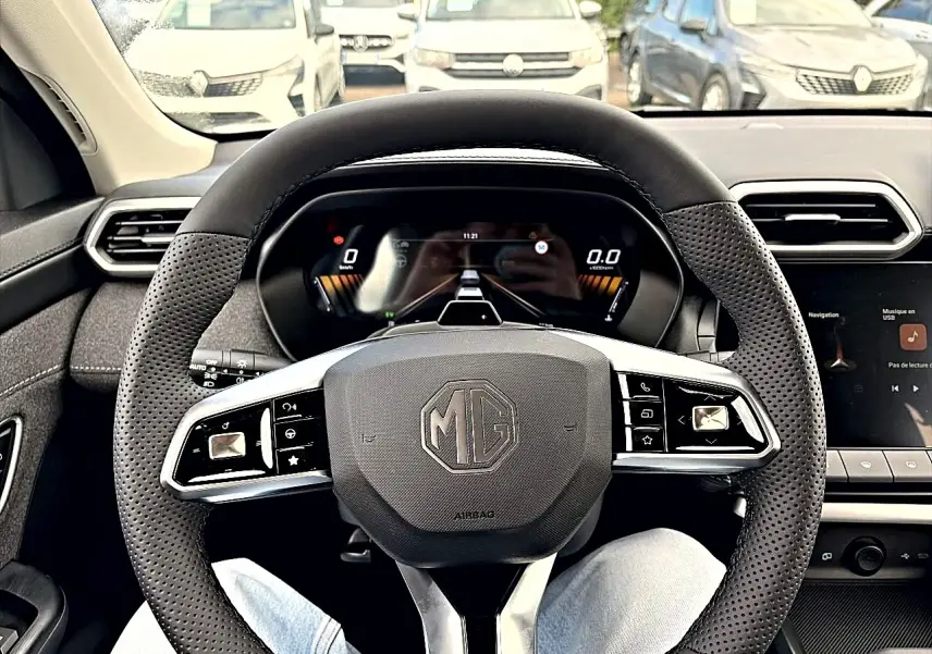Vue intérieure centrée sur le volant perforé noir du MG ZS 1.5 hybrid 197, avec tableau de bord digital en arrière-plan.
