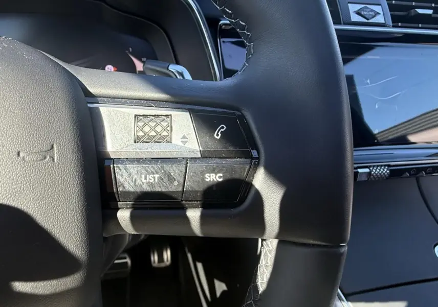 Détail du volant noir du DS7 2025 montrant les commandes intégrées côté gauche avec finition cuir et coutures apparentes.