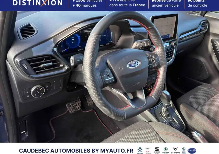 Vue intérieure côté conducteur du Ford Puma bleu 2024, volant cuir avec surpiqûres rouges et écran tactile central.