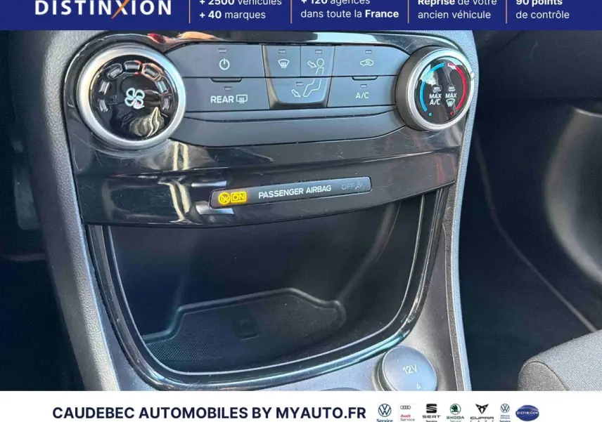 Détail de la console centrale noire avec commandes de climatisation et témoin airbag passager actif dans un Ford Puma bleu.