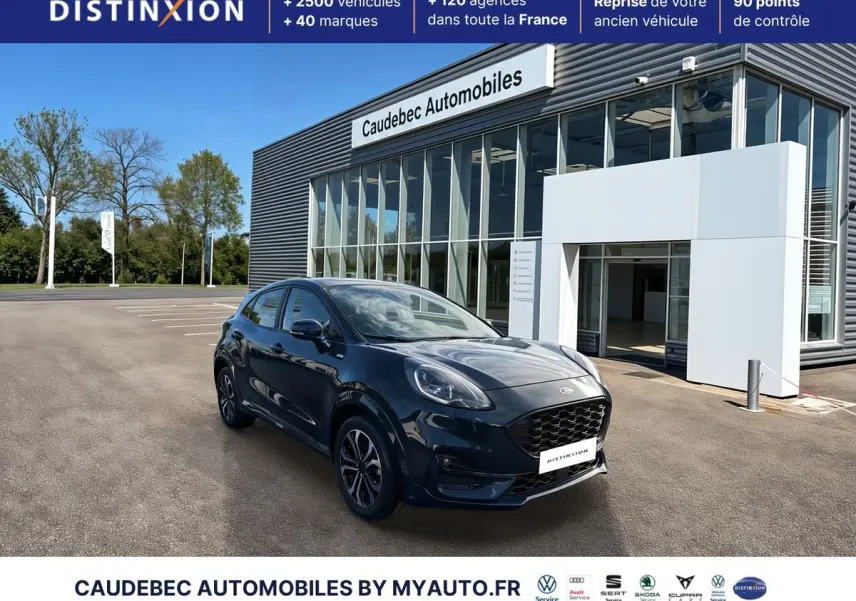 Ford Puma bleu foncé en 3/4 avant droit, avec jantes alliage 17 pouces et calandre noire, devant un showroom.