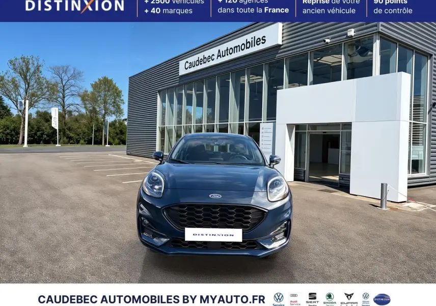 Vue avant d'une Ford Puma bleue 2024 avec calandre noire et phares LED, devant un showroom moderne.