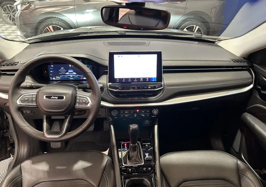 Vue intérieure avant du Jeep Compass Limited 2021, tableau de bord moderne avec écran tactile central et volant multifonction noir.