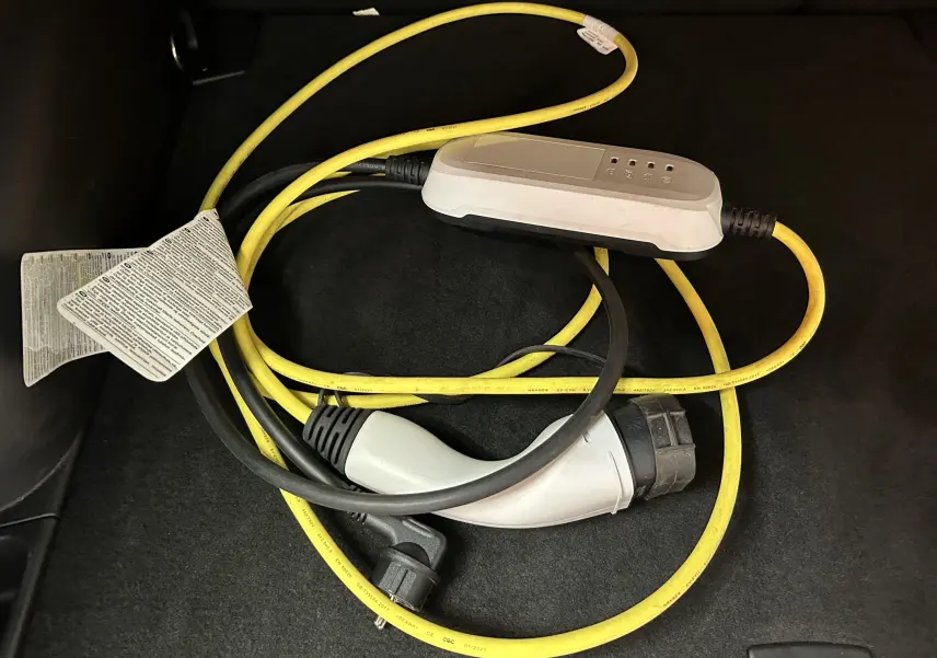 Câble de recharge jaune et noir pour Jeep Compass Limited PHEV 2021, posé sur le tapis noir du coffre.