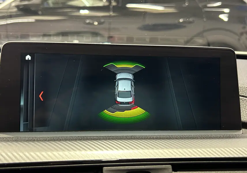 Écran central montrant l'aide au stationnement avec vue aérienne de la BMW Série 3 blanche en intérieur.