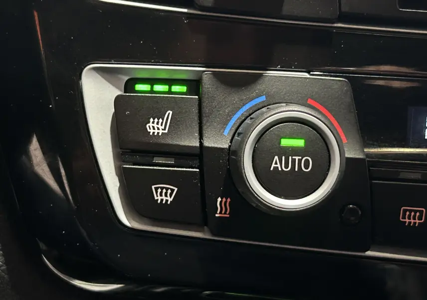 Gros plan sur les commandes de climatisation et sièges chauffants activés dans une BMW Série 3 320i blanche de 2018.