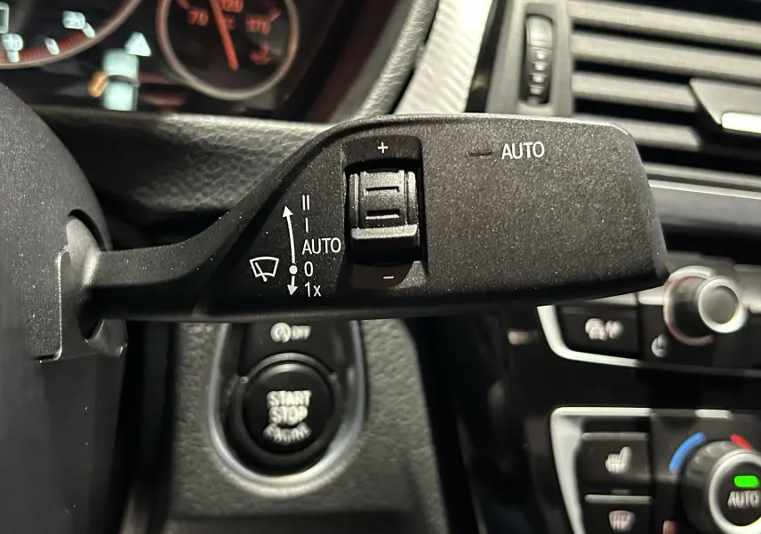 Gros plan sur la commande d’essuie-glace automatique dans l’habitacle noir d’une BMW Série 3 blanche 320i 2018.