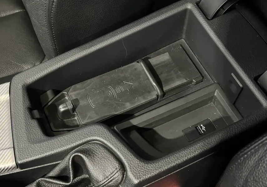 Gros plan sur la console centrale noire de la BMW Série 3 320i 2018, avec compartiment de rangement et port USB visible.