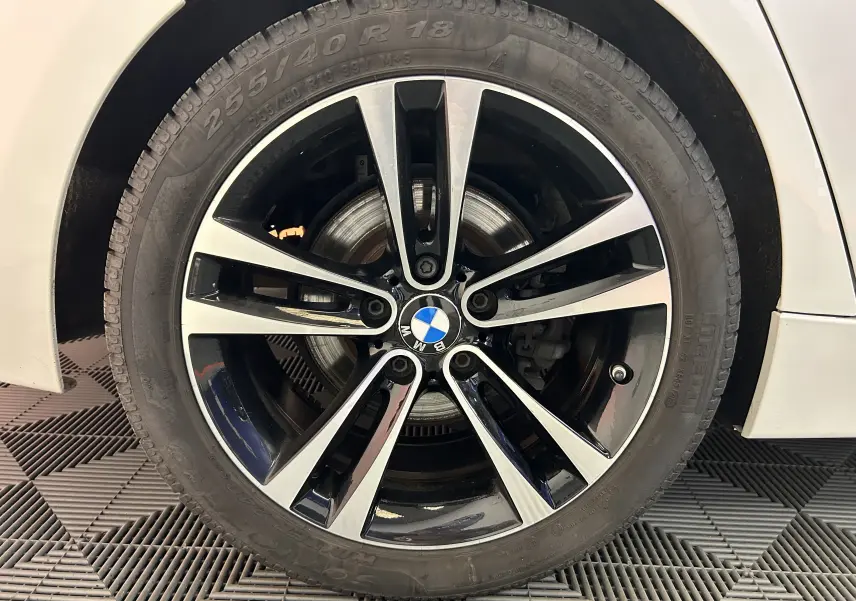 Gros plan sur la jante noire et argentée d'une BMW Série 3 blanche, modèle 320i 2018, avec pneu 255/40 R18.
