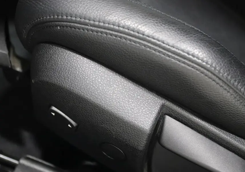 Gros plan sur la commande de réglage électrique du siège en cuir noir de la BMW Série 3 320i 2018.