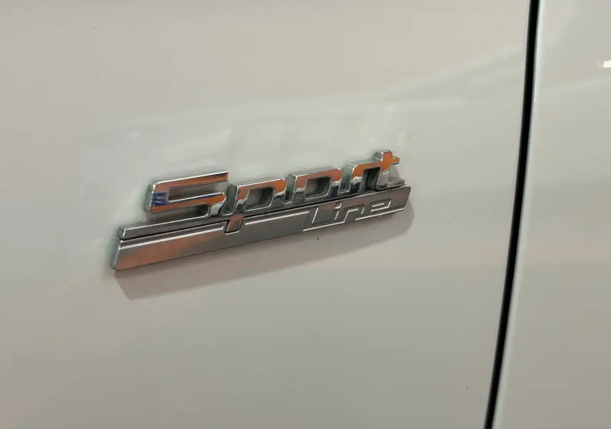 Gros plan sur l'insigne Sport Line chromé sur la porte blanche d'une BMW Série 3 320i 2018.