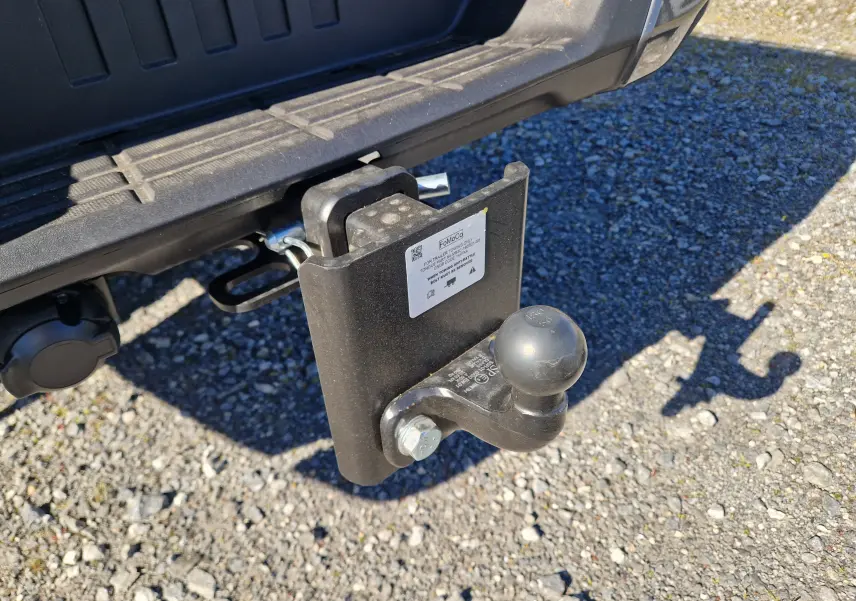 Gros plan sur l'attelage noir fixé à l'arrière du Ford Ranger Super Cabine gris carbone, avec ombre portée au sol.