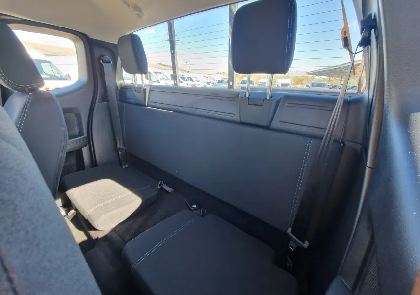 Vue intérieure arrière du Ford Ranger Super Cabine gris carbone, montrant les sièges arrière compacts et la vitre arrière.