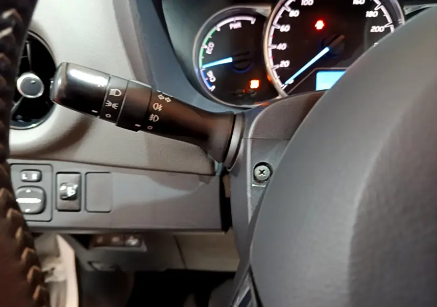 Vue rapprochée du tableau de bord et du commodo d'éclairage d'une Toyota Yaris blanche hybride 2020, côté gauche.