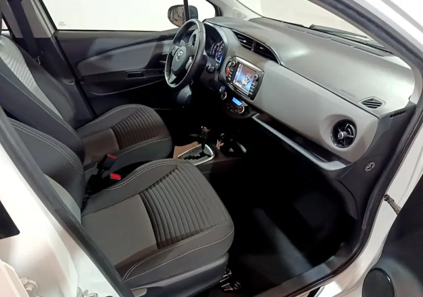 Vue intérieure côté conducteur de la Toyota Yaris blanche 2020, montrant sièges et tableau de bord moderne.