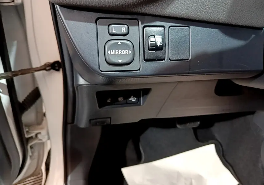 Vue rapprochée côté gauche de la Toyota Yaris blanche 2020 montrant les commandes des rétroviseurs et réglage des phares.