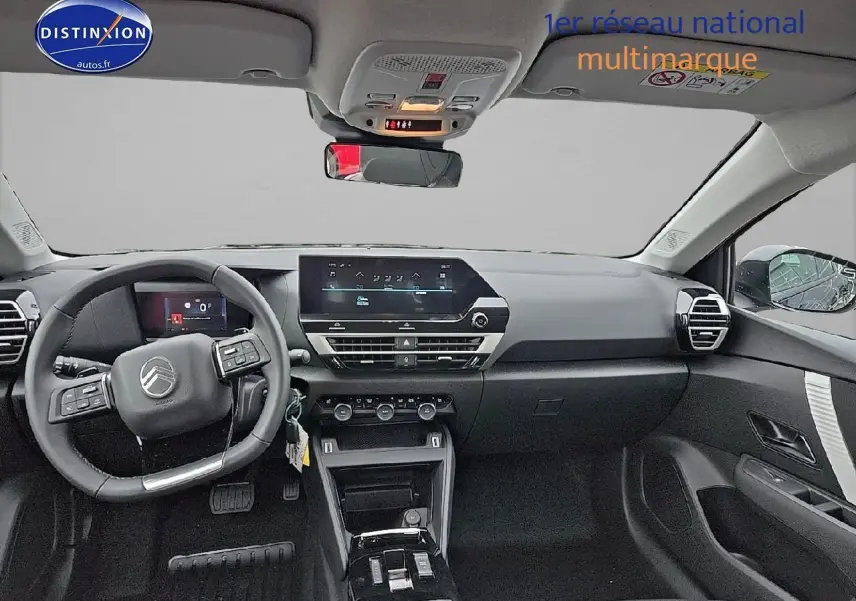 Vue intérieure avant du tableau de bord et volant cuir noir d'une Citroën C4 hybride 2025 avec écran tactile et commandes au volant.