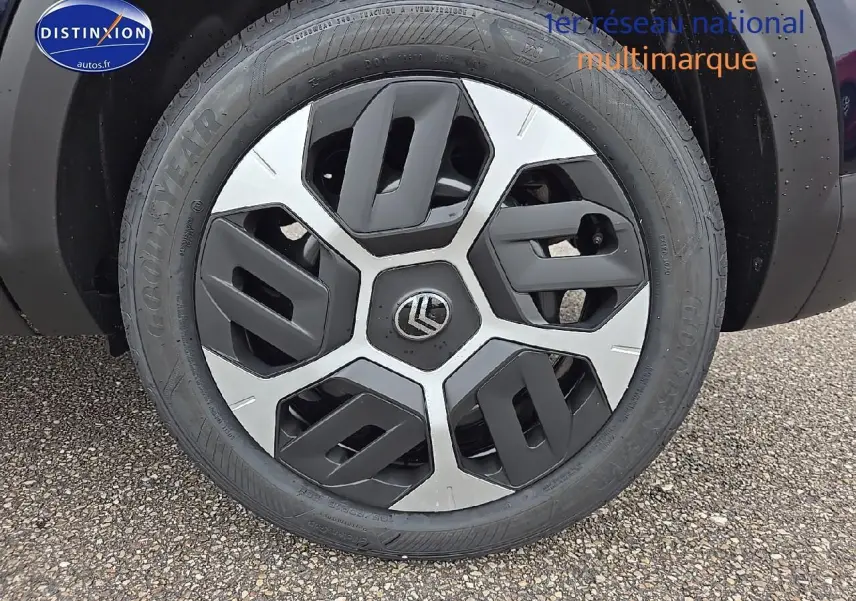 Gros plan sur la roue avant gauche noire métal de la Citroën C4 hybride avec jante alliage 18 pouces bicolore.