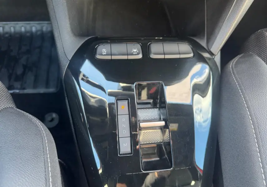 Gros plan sur la console centrale noire de l’Opel Corsa 2025 avec levier de boîte auto et boutons de contrôle.