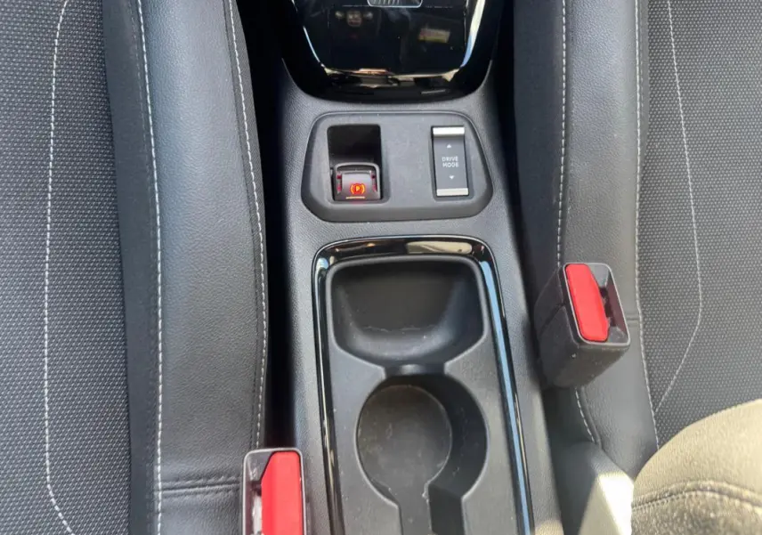 Vue rapprochée du console central noir entre les sièges avant gris d’une Opel Corsa rouge 2025.