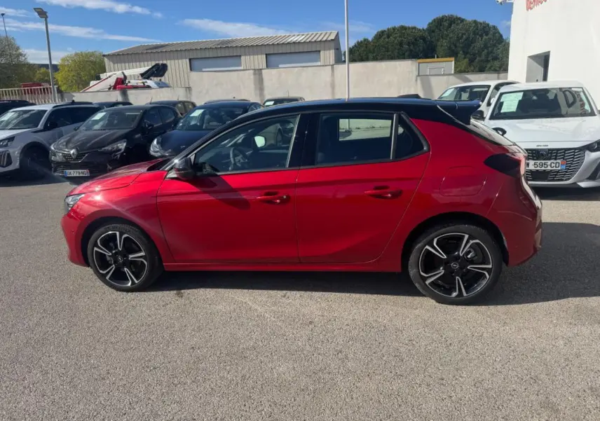Opel Corsa rouge vue de profil côté gauche, avec jantes alliage noires et toit noir contrasté.
