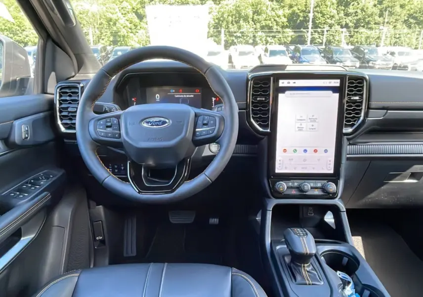 Intérieur du Ford Ranger 2025 avec volant cuir multifonctions, écran tactile vertical et sellerie noire avec surpiqûres contrastées.
