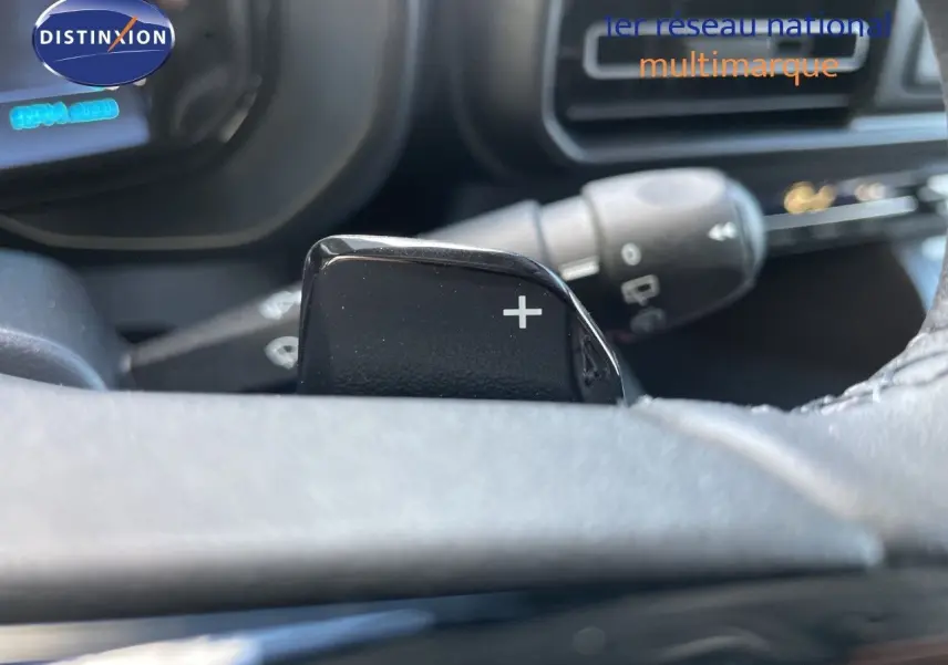 Gros plan sur la palette de changement de vitesse "+" du volant d'un Citroën Berlingo noir Perla Nera, intérieur moderne.