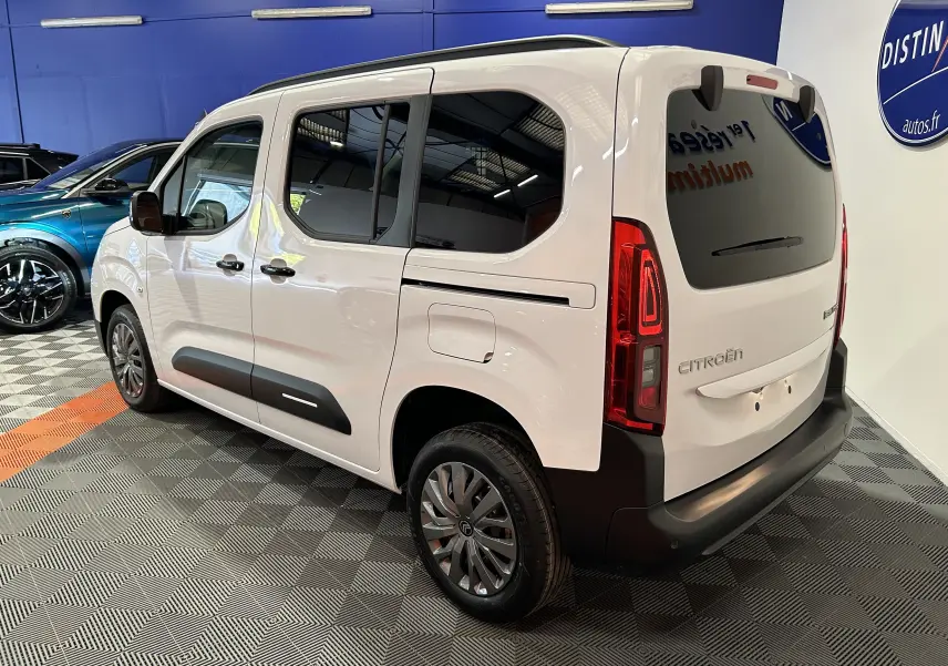 Vue 3/4 arrière droite du Citroën Berlingo Multispace blanc Kaolin avec vitres surteintées et barres de toit noir brillant.