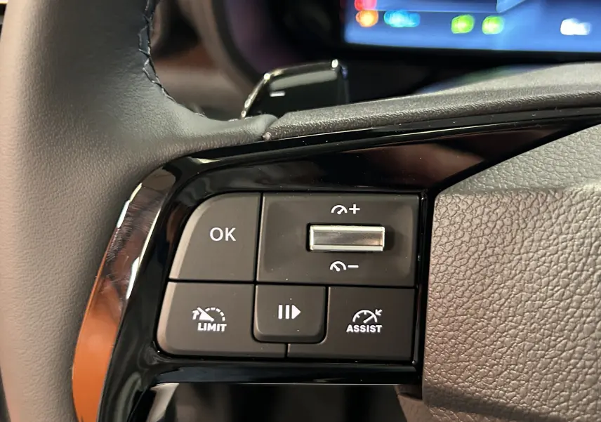 Gros plan sur les commandes au volant noir du Citroën Berlingo Multispace blanc Kaolin, avec écran tactile en arrière-plan.