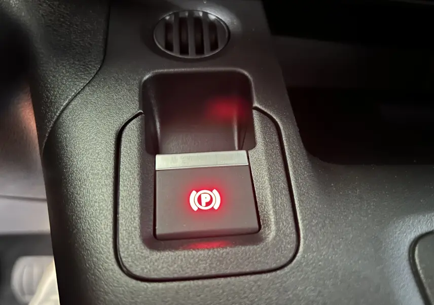 Gros plan sur le bouton de frein à main électrique allumé dans l'habitacle du Citroën Berlingo Multispace blanc Kaolin.