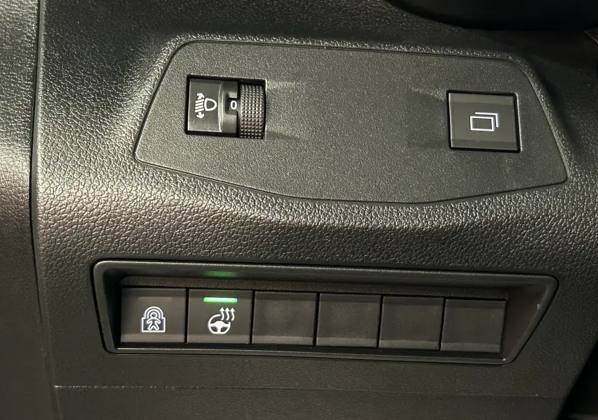 Gros plan sur les commandes noires du tableau de bord du Citroën Berlingo Multispace III Ph.2, avec bouton de chauffage de volant allumé.