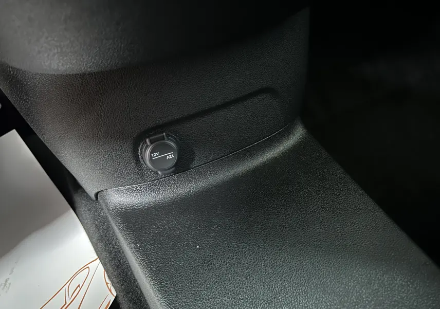Détail intérieur montrant une prise 12V sur la console centrale noire du Citroën Berlingo Multispace blanc.